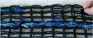 3. Choose an eyelash yarn and start weaving in the centre mesh row. Weave over and under the mesh yarns. Leave the eyelash yarn tails hanging loose.